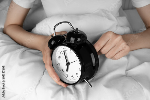 Woman's hand Starts up black alarm clock in her bed