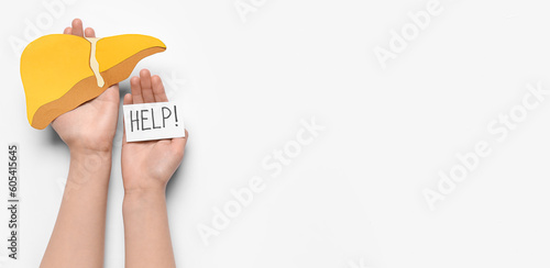 Female hands holding liver and paper with text HELP on white background with space for text