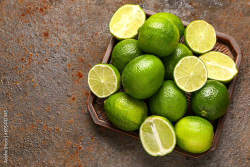 Tray with fresh limes on brown background