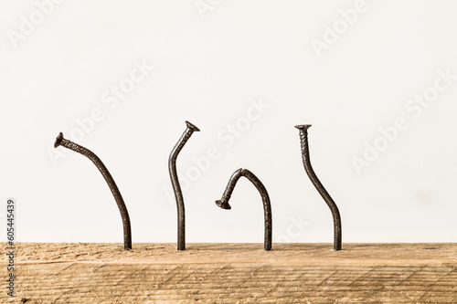 Crooked nails in a wooden board with white background. Try and fail concept.