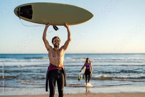 A happy surfer with his board holding it in the air.