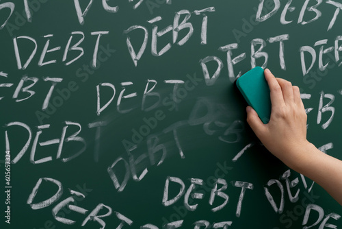 Hand erasing word debts on blackboard