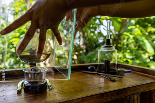 Bali, Indonesia A woman prepares Luwak coffee at a coffee plantation for degustation through percolation.