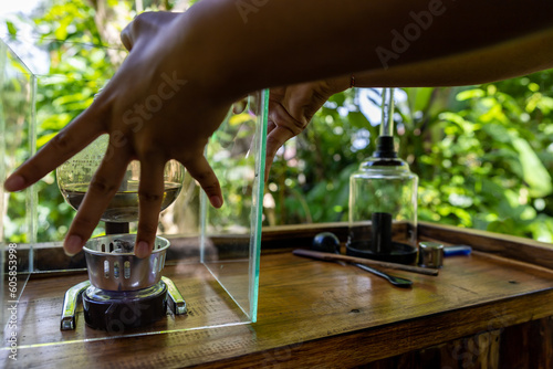 Bali, Indonesia A woman prepares Luwak coffee at a coffee plantation for degustation through percolation.