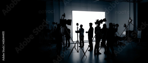 Silhouette images of film production, behind the scenes or b-roll of making video commercial movie, Film crew light man and cameraman working together with film director in studio, Film industry,