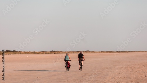 Women riding bicycles on the sandy shore of Fano Island on a sunny day. Denmark