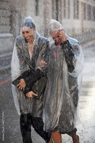 Businesswomen in ponchos walking in rainy street