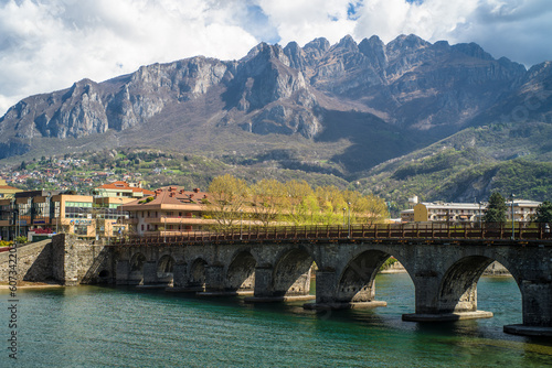 Buildings of the city of Lecco on the banks of the river Adda. Bridges and an island with mountains in the background
