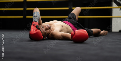 Unconscious Asian boxer lay on floor referee counting down knockout in the ring at fitness gym. Boxing is fighter sport training need body muscular strength, power fist and sweating to become champion