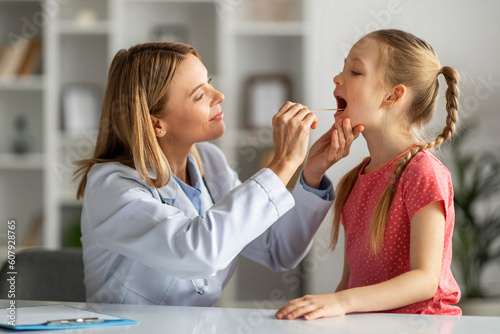 Kids Healthcare. Female doctor pediatrician checking throat of little girl patient