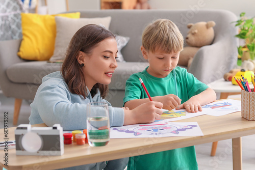 Nanny with little boy drawing at home