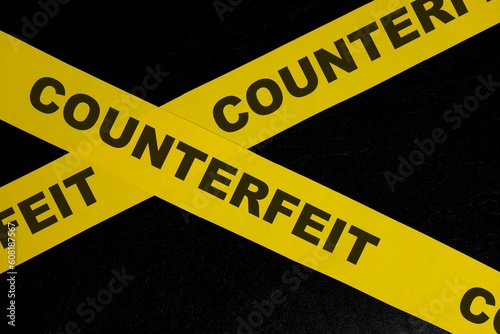 Counterfeit product and item caution and warning concept. Yellow barricade tape with word in dark black background.