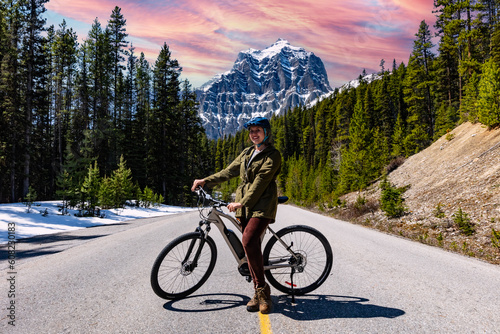 Woman cyclist on the track. Road to the mountains. Trail into the mountains and into the forest. Banff National Park.