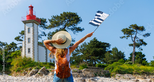 tourism in Brittany- Lighthouse on atlantic coast and woman tourist holding breton flag- Brittany in France (phare de Sainte Marine)