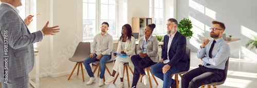 Diverse, multiracial, multiethnic audience sitting on chairs at business training workshop lesson, listening to professional team coach speaker, and learning about new sales techniques and lifehacks