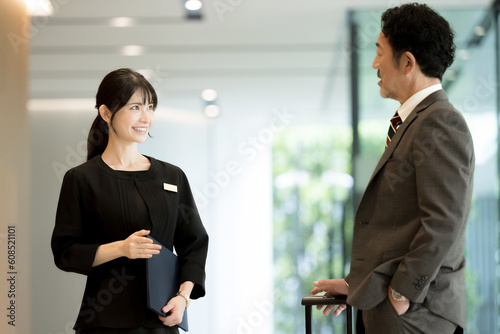 A scene of a woman in the hospitality industry giving information at a reception desk in a hotel during a business or travel trip in Japan or Asia 