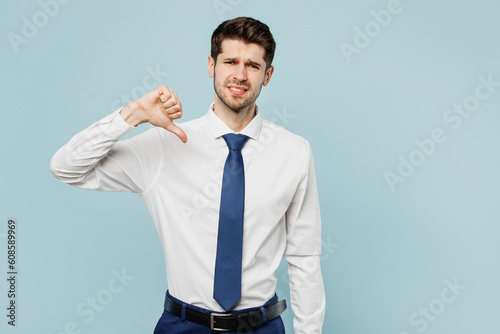 Young successful employee business man corporate lawyer wear classic formal shirt tie work in office showing thumb down dislike gesture isolated on plain pastel light blue background studio portrait.