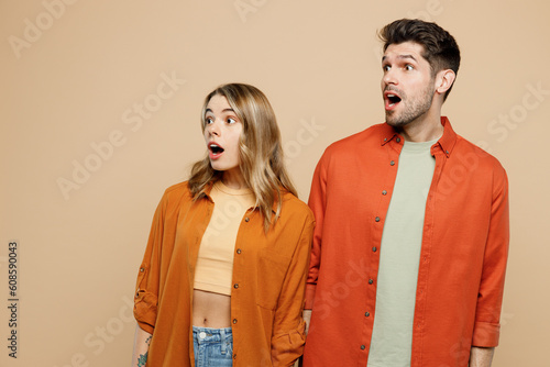 Young shocked surprised amazed impressed couple two friends family man woman wear casual clothes looking aside on area together isolated on pastel plain light beige color background studio portrait.