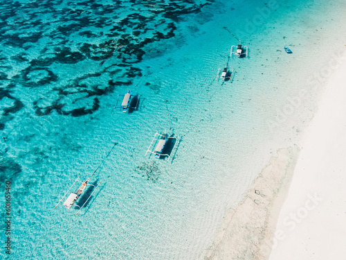 Blue ocean and beach with fishing boats in tropics. Aerial view.