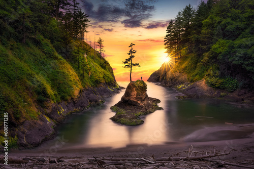 Sunset at Dead Man's Cove located at Cape Disappointment State Park in Ilwaco. A tourist young woman (female) in blue raincoat enjoys the sunset on a small hill, Cape Disappointment, Washington, USA