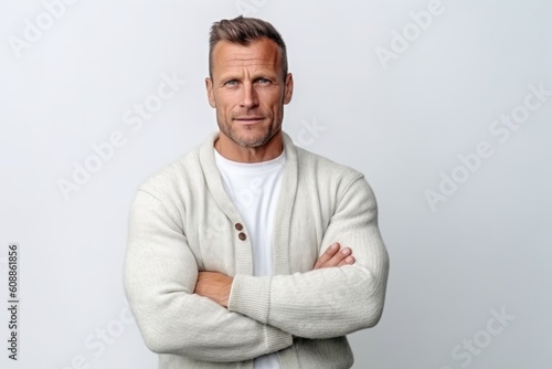 Portrait of handsome middle-aged man in white sweater standing with arms crossed against white background