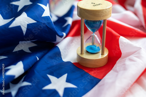 Hourglass and USA flag, soft focus, copy space