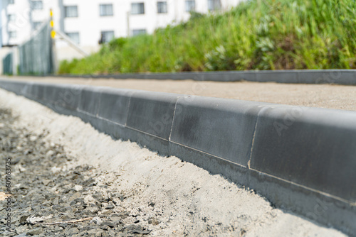 Construction of a pedestrian path. Paving of pedestrian paths on city streets. Road curbs and sidewalks. New curbs close up. Curbs detail. Soft focus