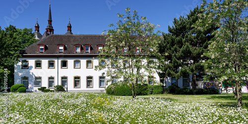house of the st. heribert old people's home of caritas in cologne deutz in front of a blooming spring meadow