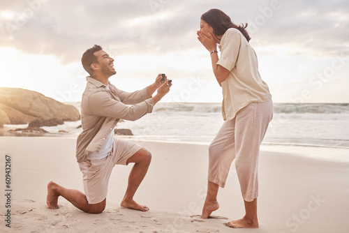 Couple, engagement proposal and surprise at beach with smile, happiness or love on vacation in sunset. Man, woman and ring with marriage offer by ocean with smile, excited face or together on holiday