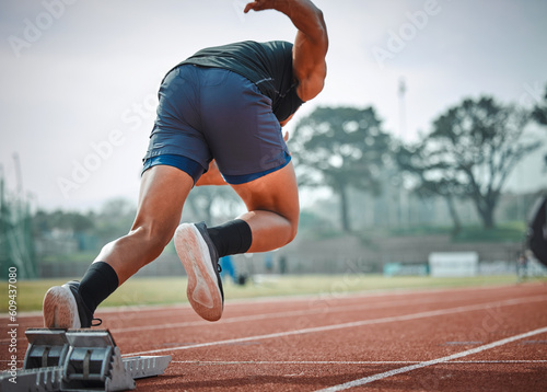 Stadium, man running and start block of athlete on a runner and arena track for sprint race training. Back, run and sports exercise of male person in marathon for fitness and workout outdoor on field