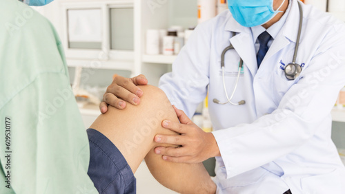 The orthopedic doctor or surgeon in white gown examined the patient with knee pain problem.White clean table or bed with blur background.Knee ligament or meniscus sport injury.Orthopaedic unit.