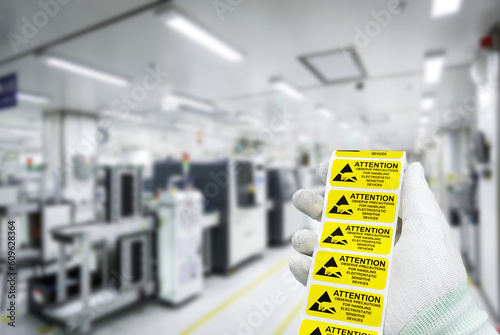 Hand holding "CAUTION Electrostatic Sensitive Devices" label at static free workstation,Antistatic area in electronic industry.