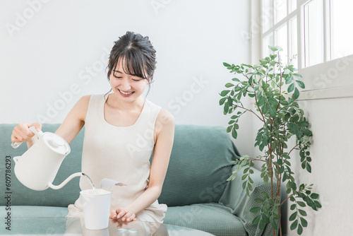 家でカップラーメンにケトルでお湯を注ぐアジア人女性 