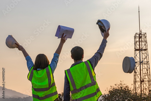 Professional team Engineer managers workers working outdoors with telecommunication antenna and sunset background..