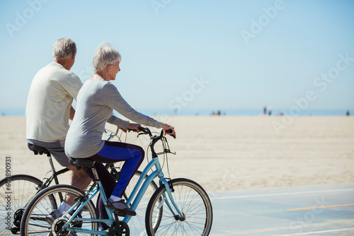 Senior couple riding bicycles on beach