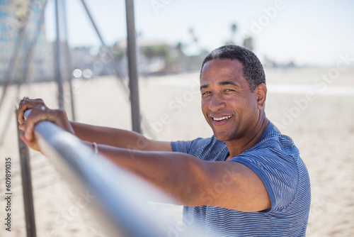 Portrait of senior man leaning on bar at beach playground