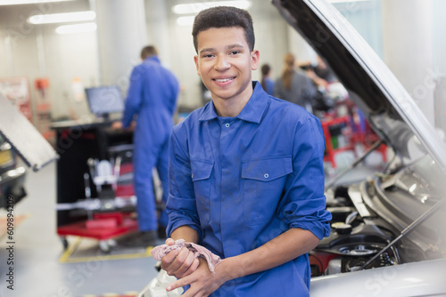 Portrait smiling mechanic leaning on car in auto repair shop
