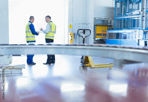 Workers in reflective clothing talking at warehouse loading dock doorway