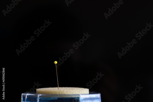 yellow pin stuck in foam in a black background