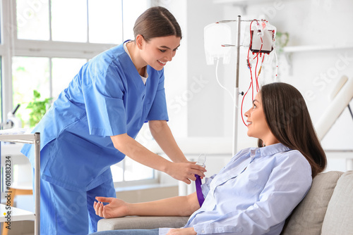 Female nurse preparing young donor for blood transfusion in clinic