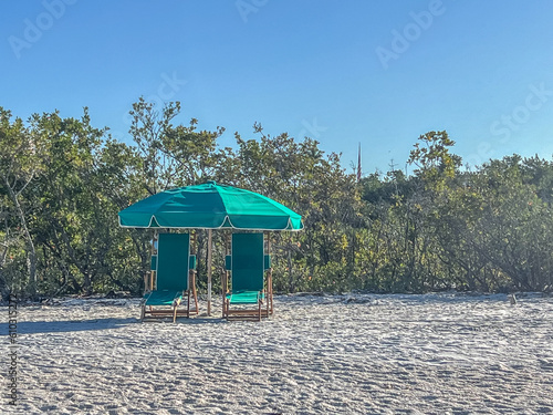 empty chase lounge with umbrella on beach