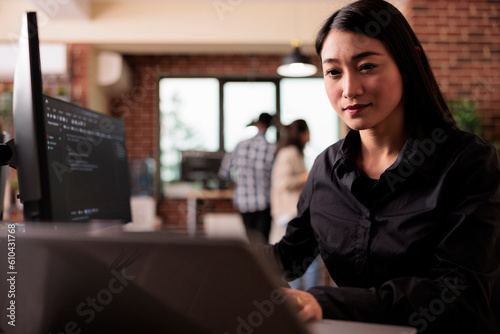 Asian freelance coder analyzing compiling html code on computer display, working on interface development. Programming engineer using terminal window with firewall server data in it big data agency