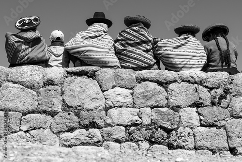 Peruvian indigenous Quechua people on ancient Inca wall in black and white, Chinchero, Cusco, Peru.
