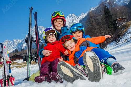 Mom, boy and little kids sit in the snow with sport outfit