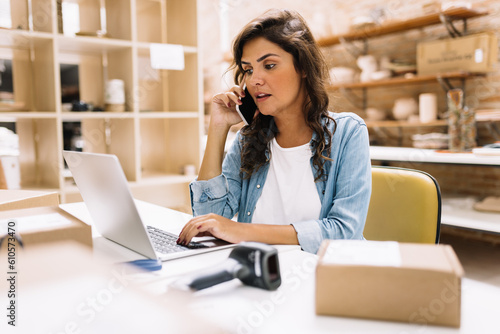Female entrepreneur speaking on the phone in a warehouse