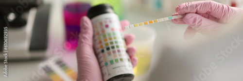 Doctor holds reagent strip for urinalysis closeup. Control analysis of urine in laboratory concept