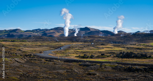 Asphalt road in Iceland in Mývatn geothermal area. steam from geothermal power station.