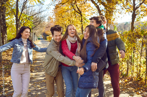 Group of satisfied happy young friends having fun in autumn park.