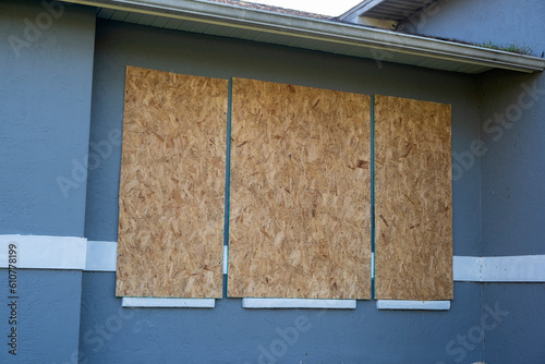 Boarded up windows with plywood storm shutters for hurricane protection of residential house. Protective measures before natural disaster in Florida