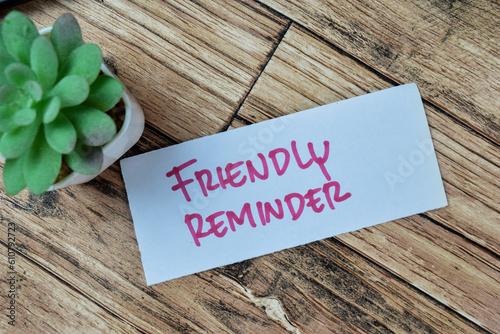 Concept of Friendly Reminder write on sticky notes isolated on Wooden Table.